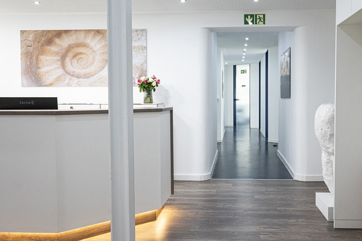 Zahnarztpraxis Brandingprojekt. Wir sehen einen Gang in einer Zahnarztpraxis entlang. Es hängen individuelle Fotografien auf Alu-Dibond an den Wänden. Eine Besondere Stärke der Kreativagentur ist die Gestaltung von Innenräumen.